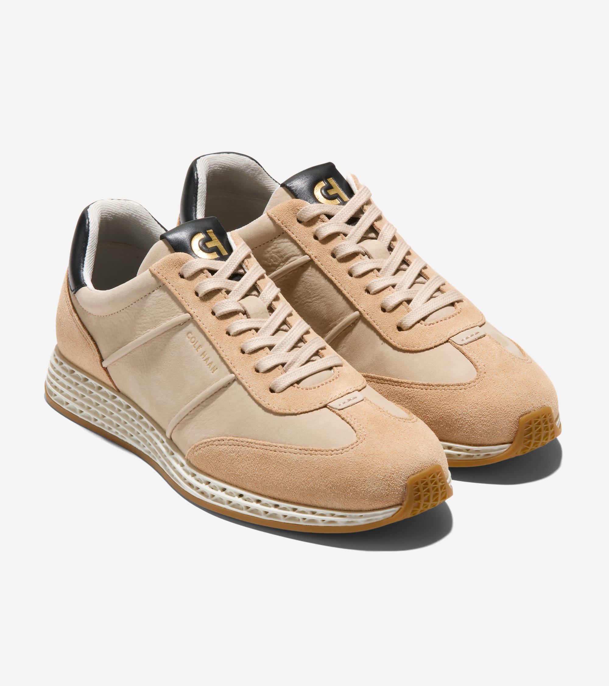 Pair of tan sneakers with suede and smooth uppers, black heel trim, gold-toned CH logo on tongue, and a textured white midsol