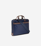 Navy blue slim briefcase with brown leather-look trim, top handles, and bottom corners. Features a navy fabric shoulder strap