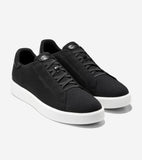 Black knit slip-on sneakers with white soles. Features black decorative laces and black leather-like trim on the heel and ton