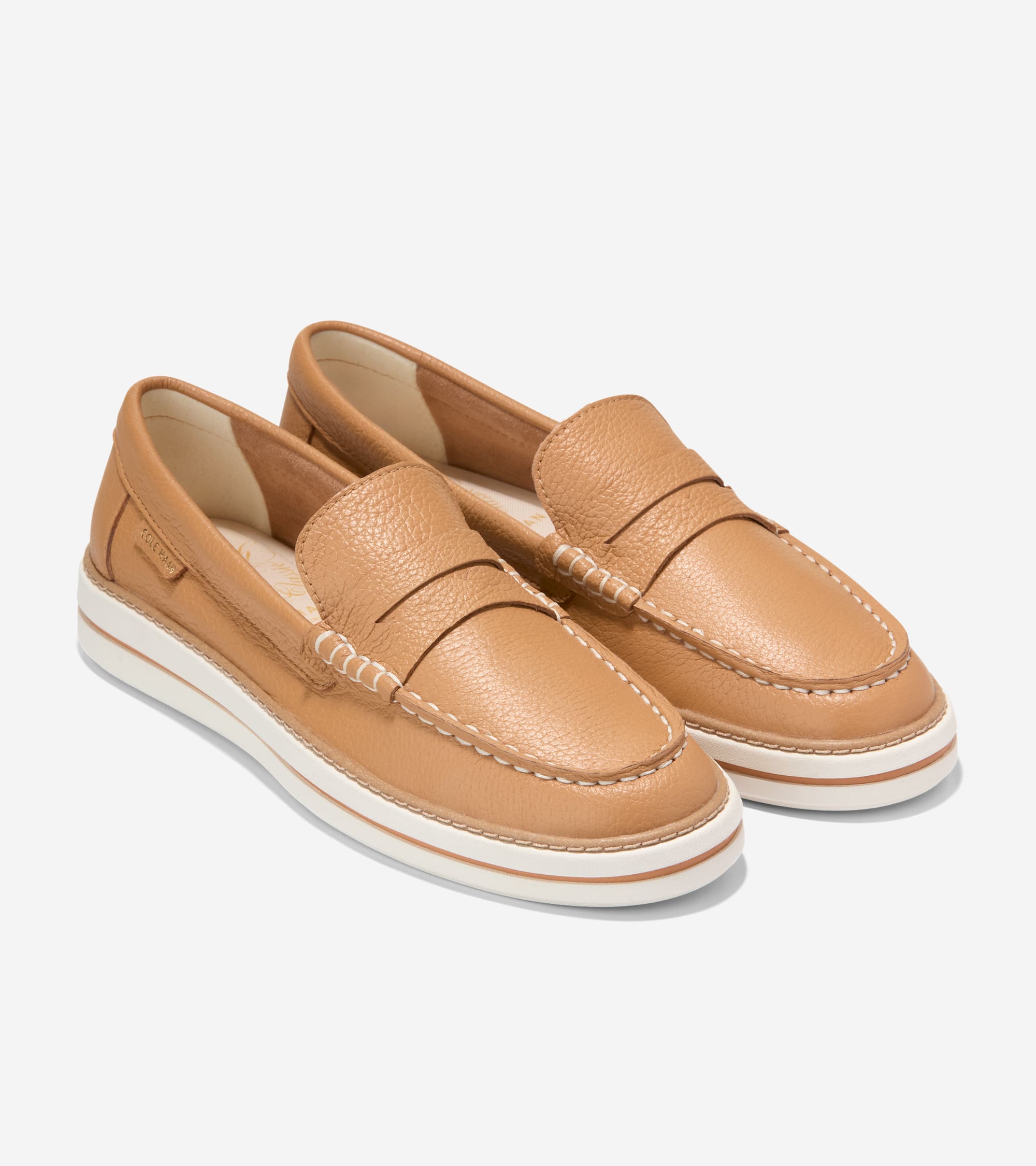 Pair of tan pebbled leather penny loafers with white contrast stitching and thick white platform soles.