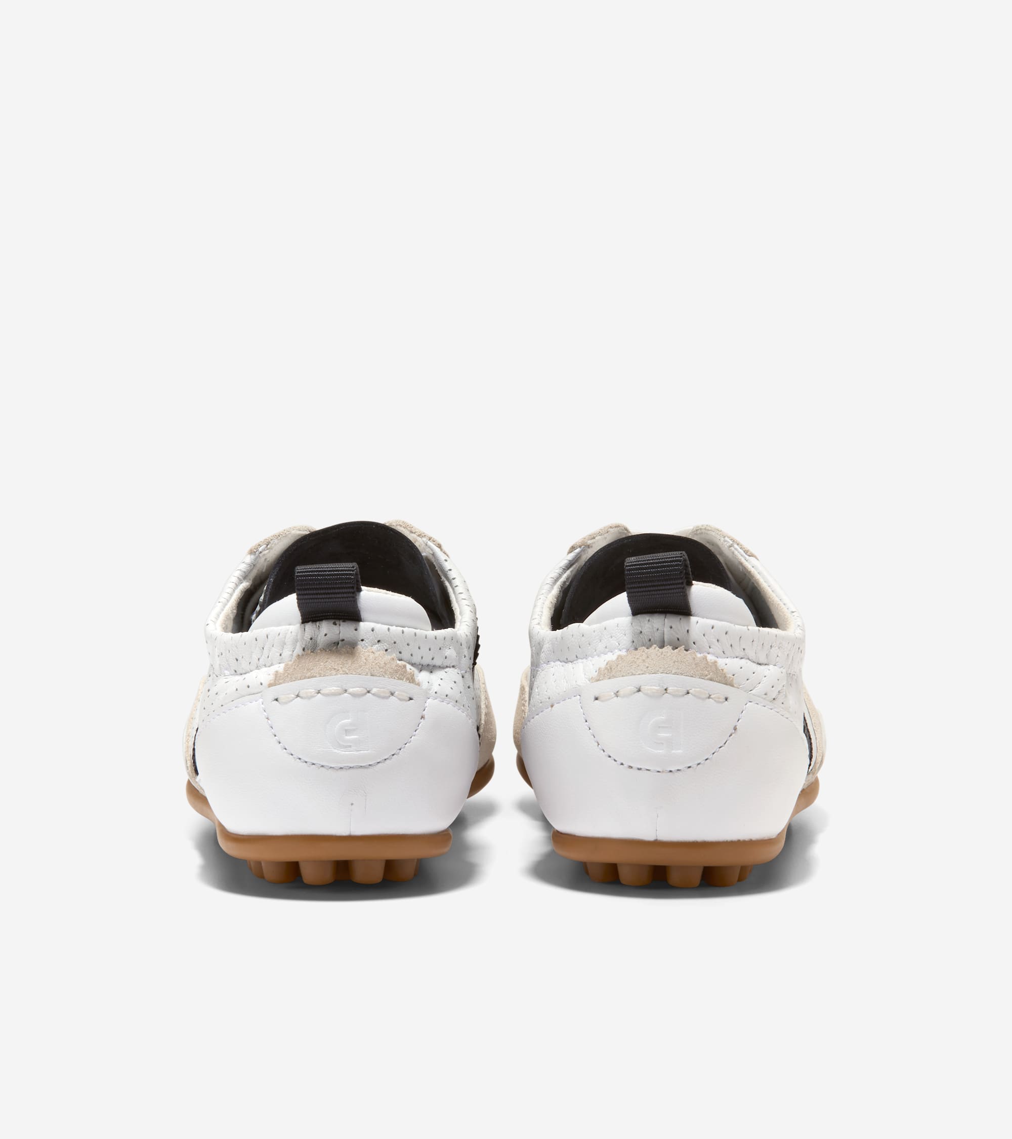 Pair of white perforated leather sneakers with beige trim, dark gray pull tabs, and brown nubbed soles. Embossed logo on heel