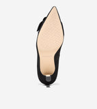 Black suede pointed-toe pump, seen from the bottom, with a tan patterned sole, low heel, and a black bow.