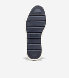 Navy blue sneaker sole with horizontal ridges, textured toe and heel patterns, and an off-white border. 'COLE HAAN GRAND OS'