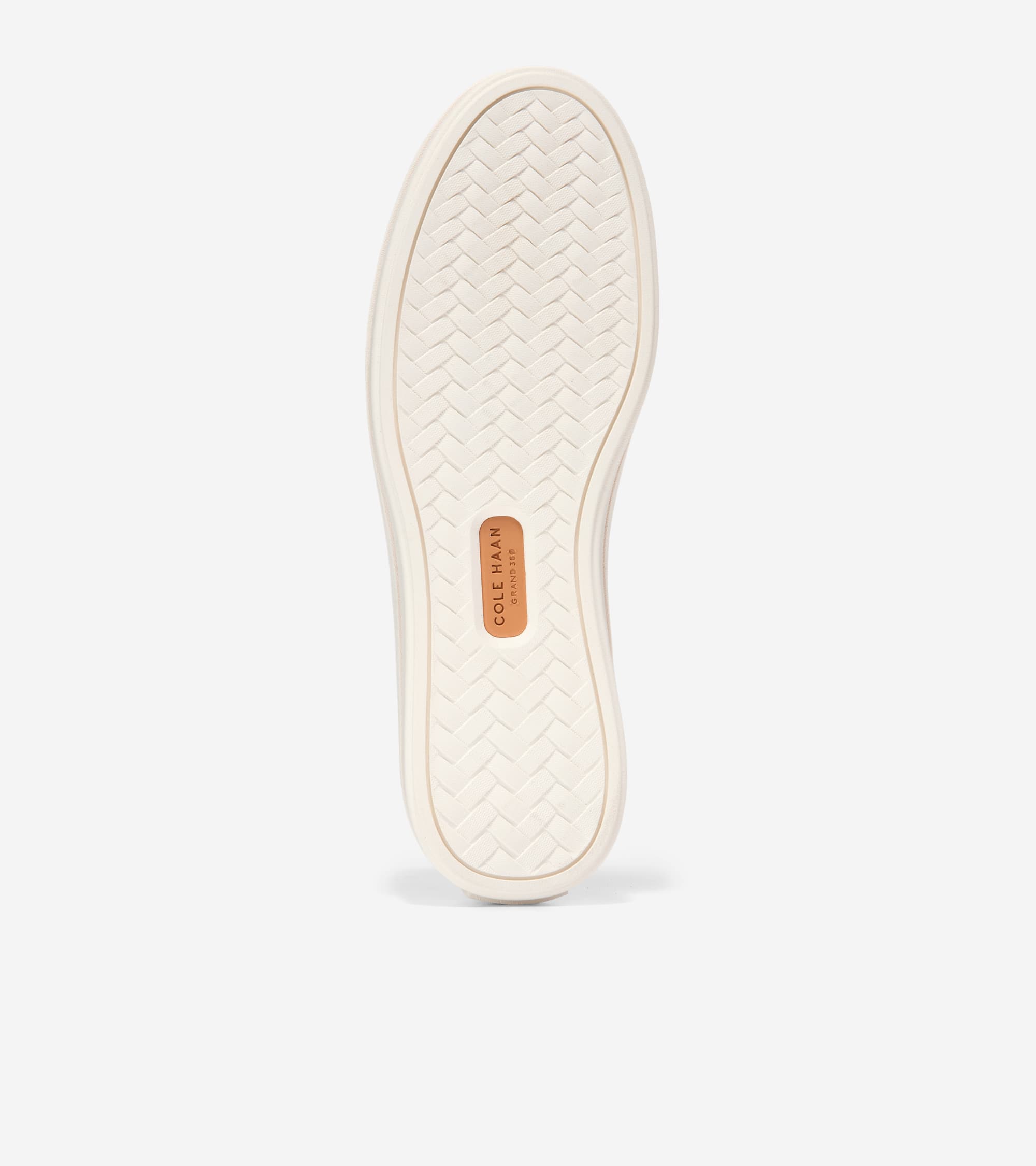 Off-white shoe sole with a herringbone-patterned tread and a brown Cole Haan Grand.ØS logo patch.