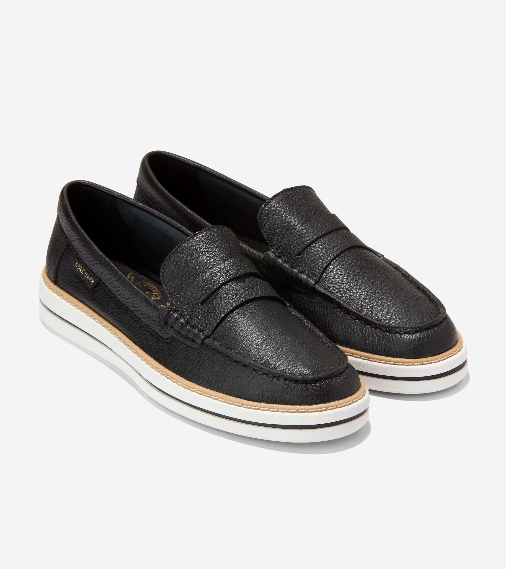 Pair of black pebbled leather penny loafers with moccasin stitching, a tan welt, and a thick white platform sole with a black