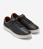 Pair of black textured leather low-top sneakers with black laces, brown collar trim, and white soles. Cole Haan logo on side.