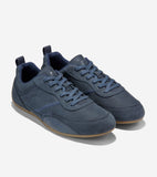 Men's slate blue low-top sneakers with pebbled and smooth leather panels, matching laces, heel pull tabs, and tan rubber sole