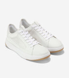 A pair of white court sneakers featuring white leather-like and mesh panels, white laces, thick white soles, and tan gum outs