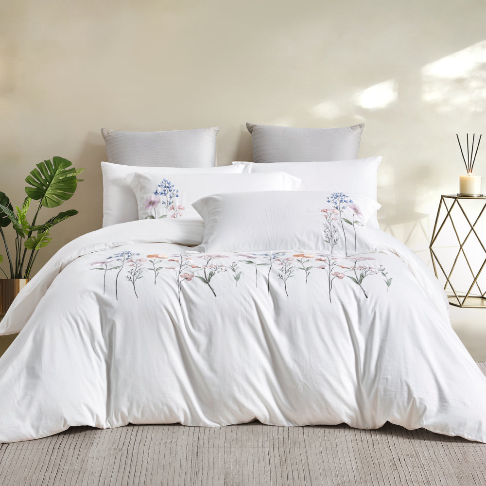 Complete bedding set styled in a modern room with a floor lamp, indoor plant, and neutral rug.