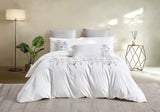 Complete bedding set styled in a modern room with a floor lamp, indoor plant, and neutral rug.