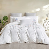 Complete bedding set styled in a modern room with a floor lamp, indoor plant, and neutral rug.