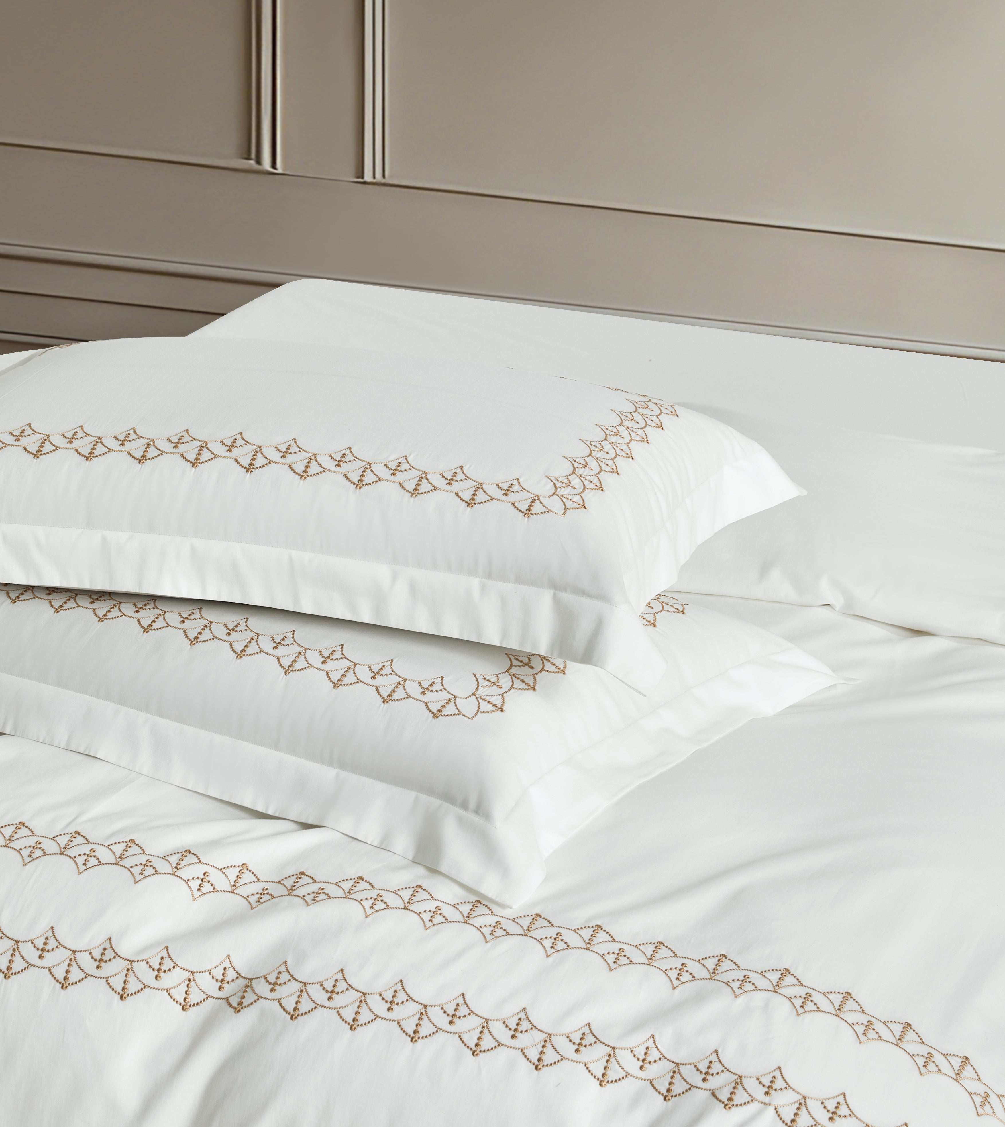 Deluxe white pillowcases with precision-stitched geometric gold patterns and professional flanged edges.