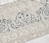 Detailed view of a white duvet cover with vertical silver floral embroidery.