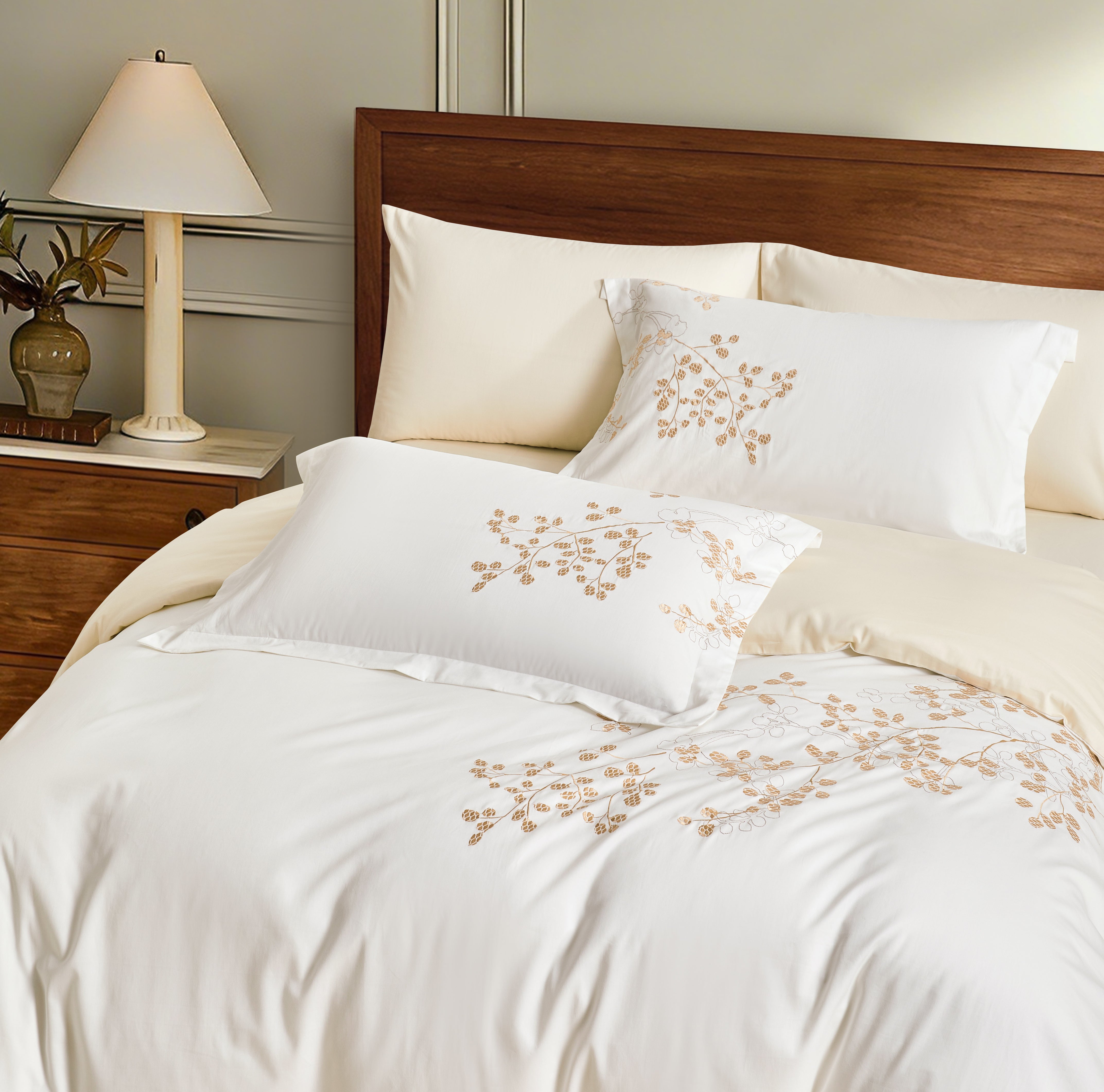 The soft white duvet is complemented by cream-colored sheets and shams, creating a layered, high-end neutral palette.
