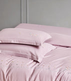 Stacked white pillowcases featuring vertical grey floral vine embroidery and flanged edges.