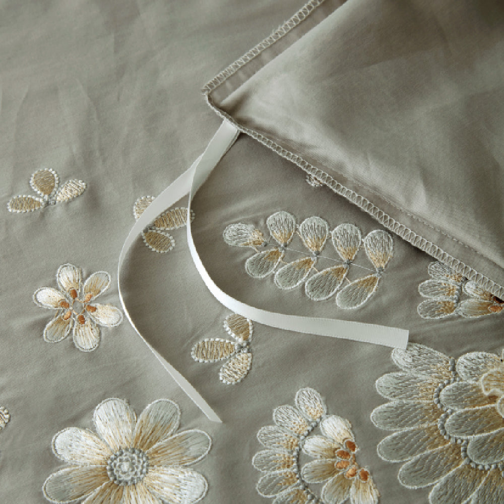Detailed macro shot of high-quality pink botanical embroidery on crisp white fabric.