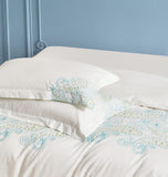 White pillowcases featuring elegant vertical orange flower and vine embroidery.