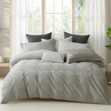 Full view of luxury white bedding with pink botanical vine embroidery in a modern bedroom.