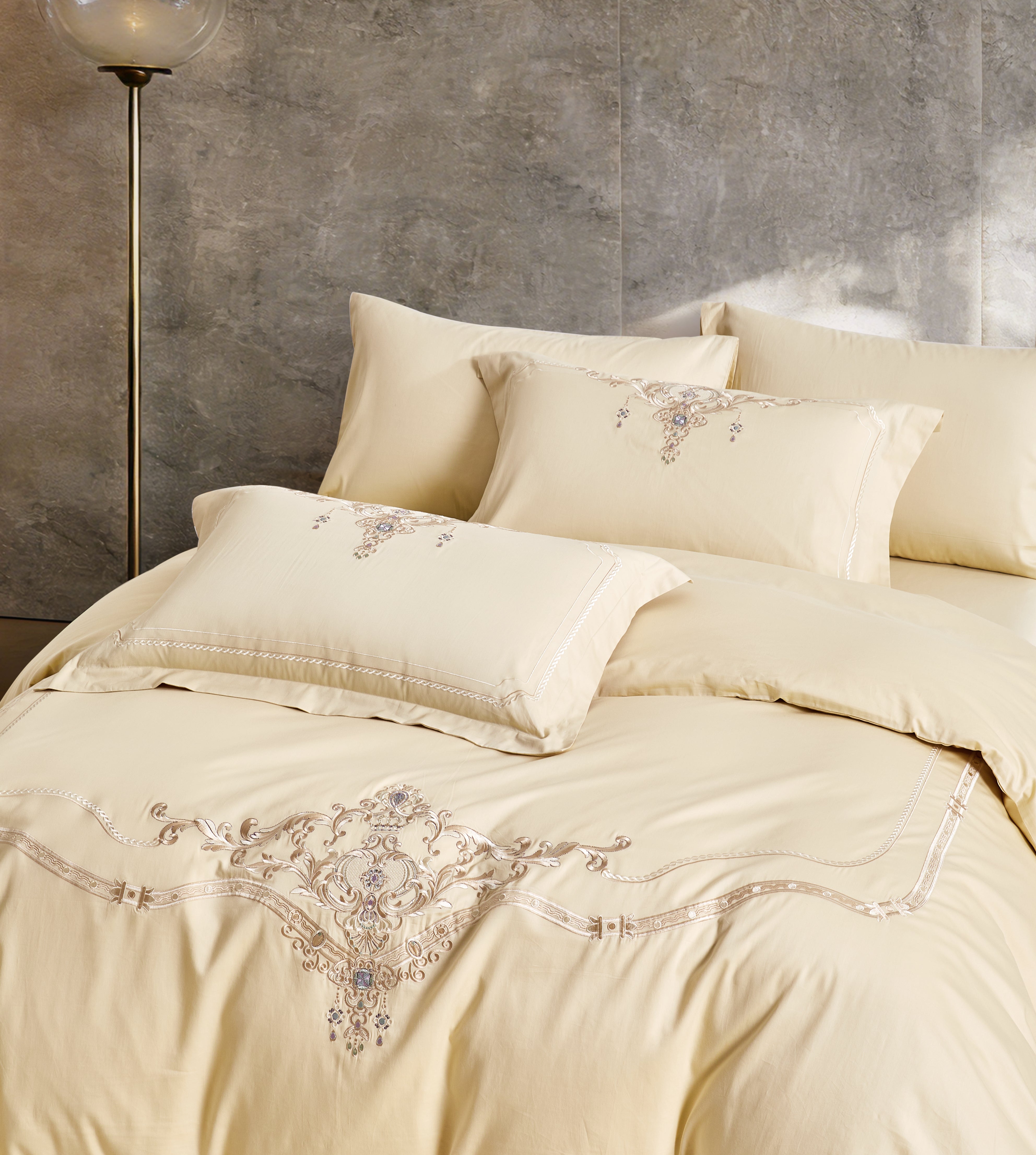 Angled view of a white luxury duvet cover featuring an embroidered botanical border.