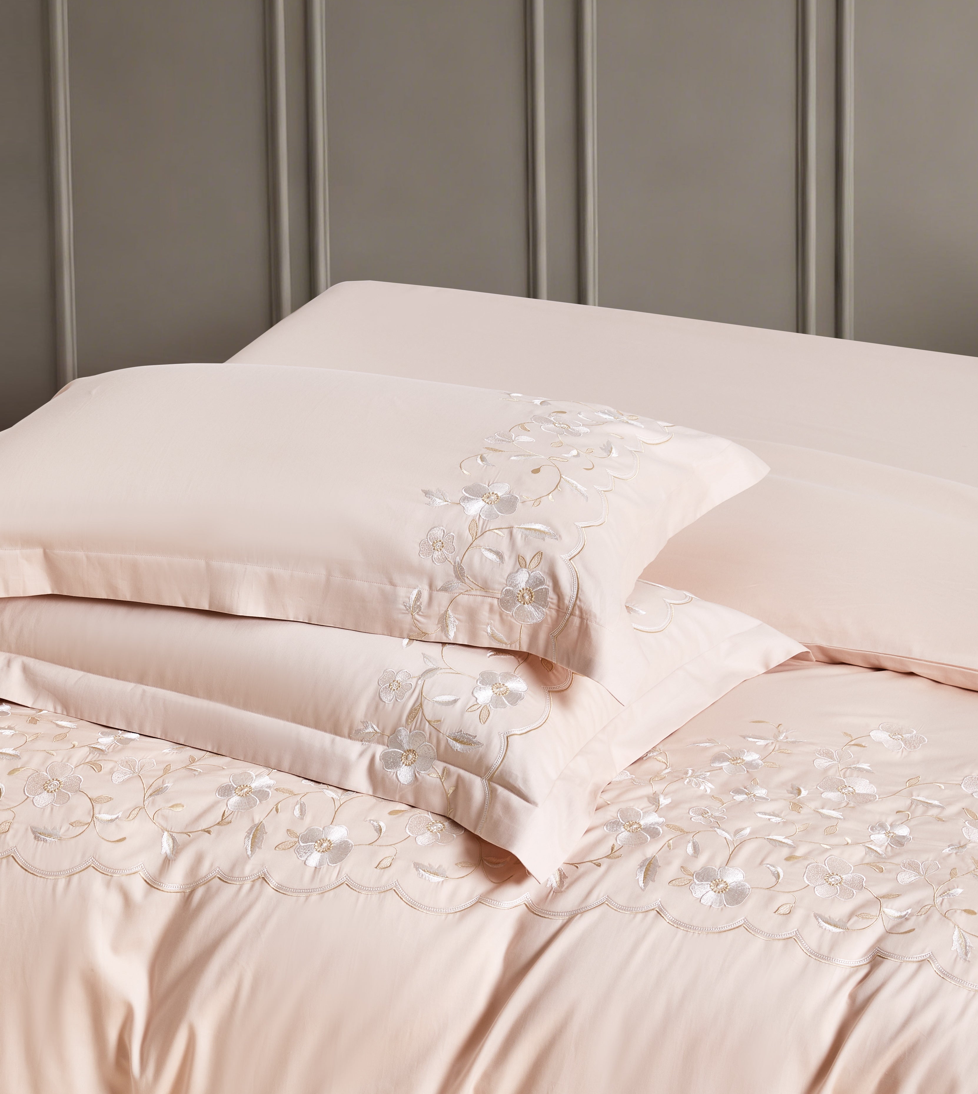 Close-up of white pillows and duvet featuring a decorative gold scalloped embroidery pattern.