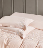 Close-up of white pillows and duvet featuring a decorative gold scalloped embroidery pattern.