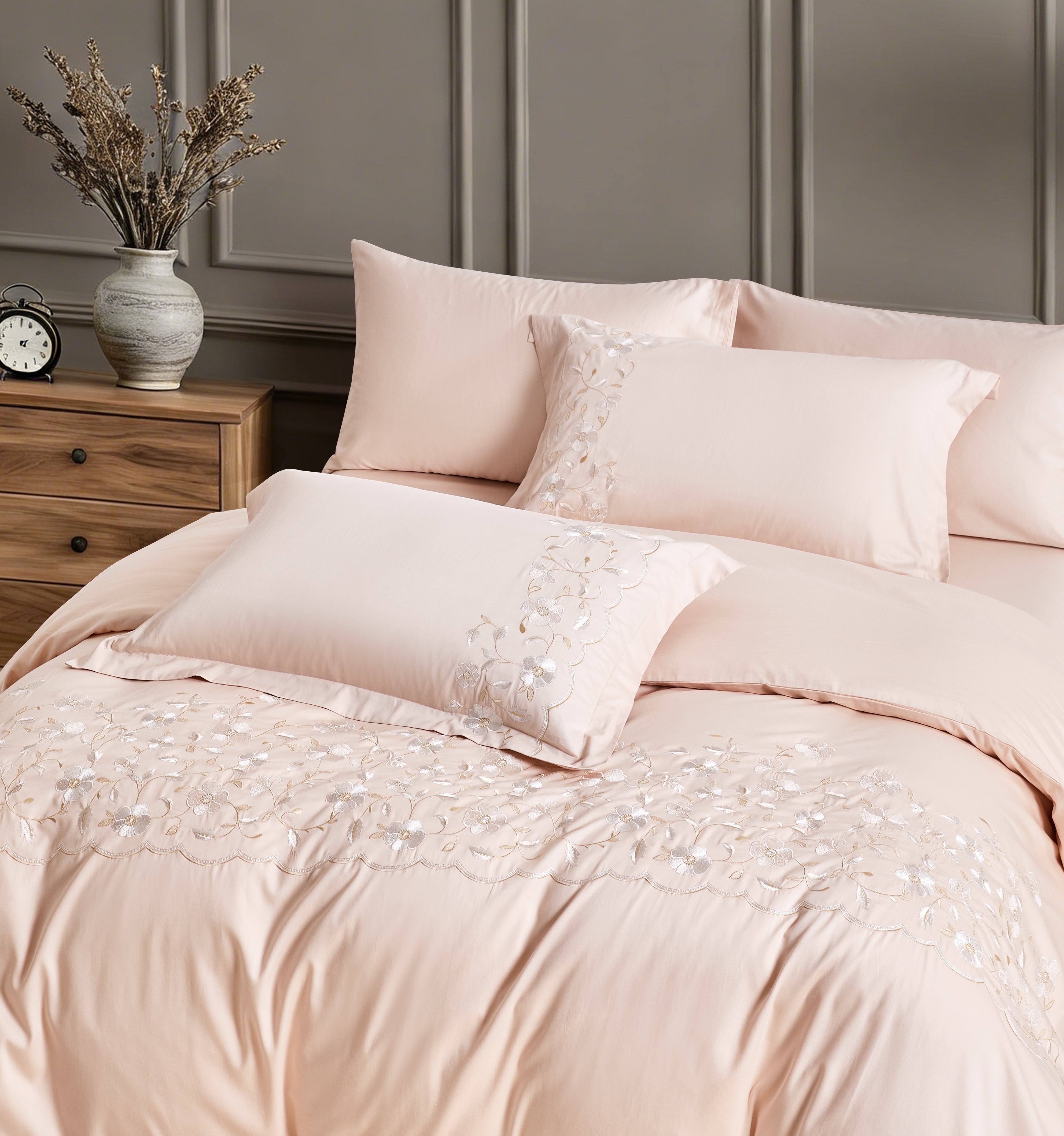 Stacked white pillowcases with elegant gold-threaded geometric embroidery along the edges.