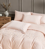 Stacked white pillowcases with elegant gold-threaded geometric embroidery along the edges.