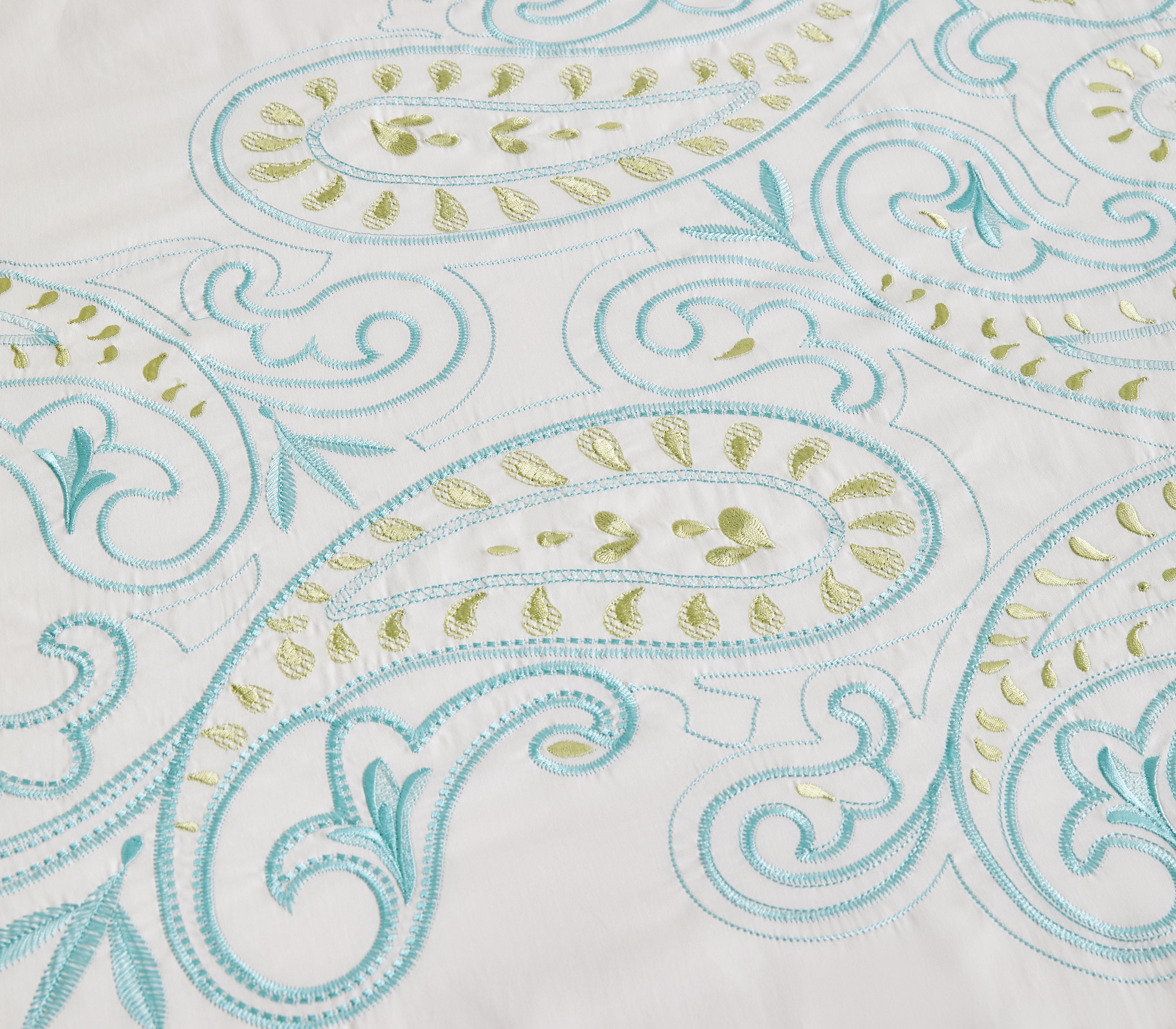 Detailed view of vibrant orange and green floral embroidery on white fabric.