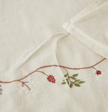 Detailed macro shot of high-quality gold floral vine embroidery on crisp white fabric.