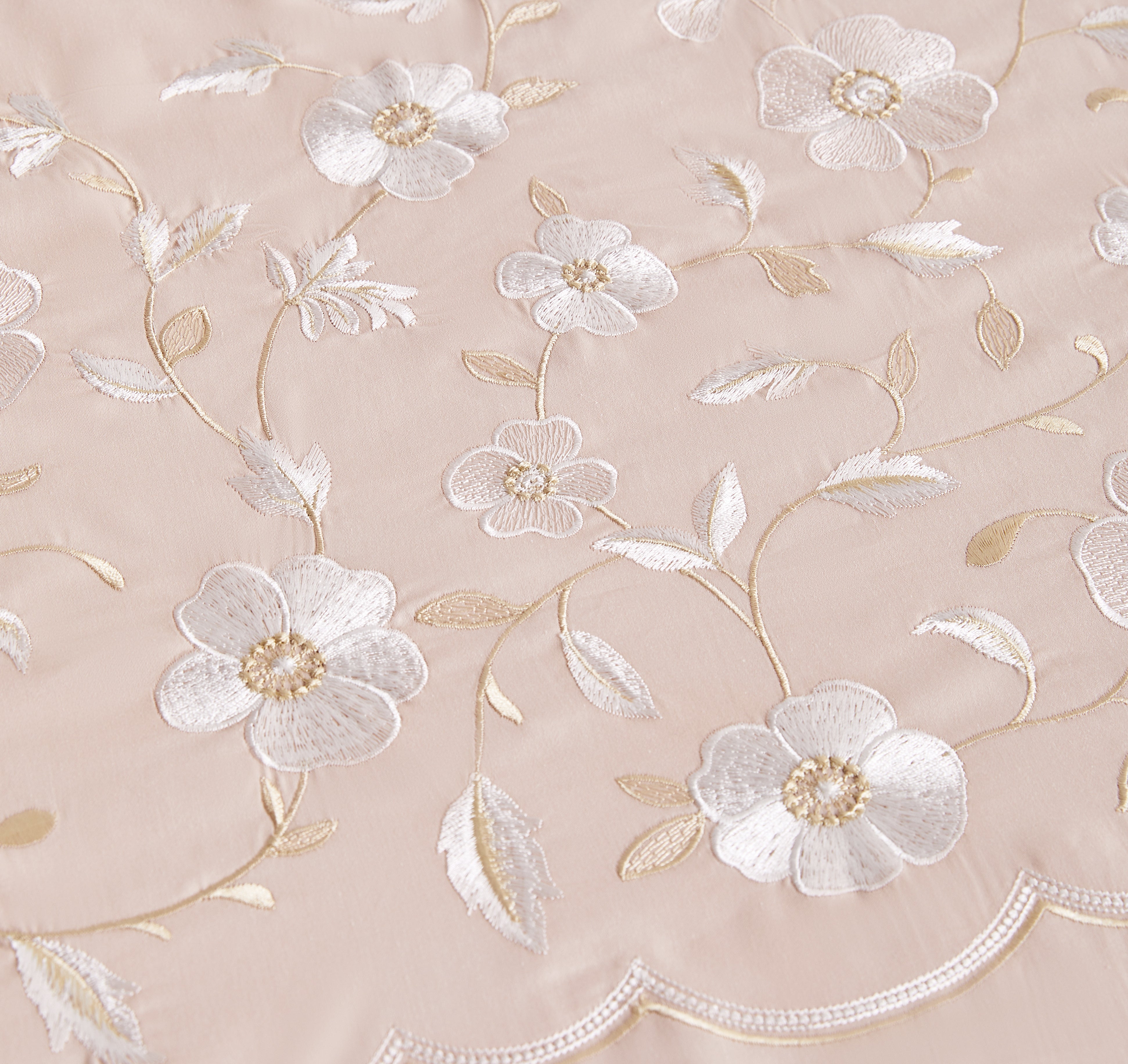 Detailed macro shot of high-density gold geometric embroidery on crisp white fabric.