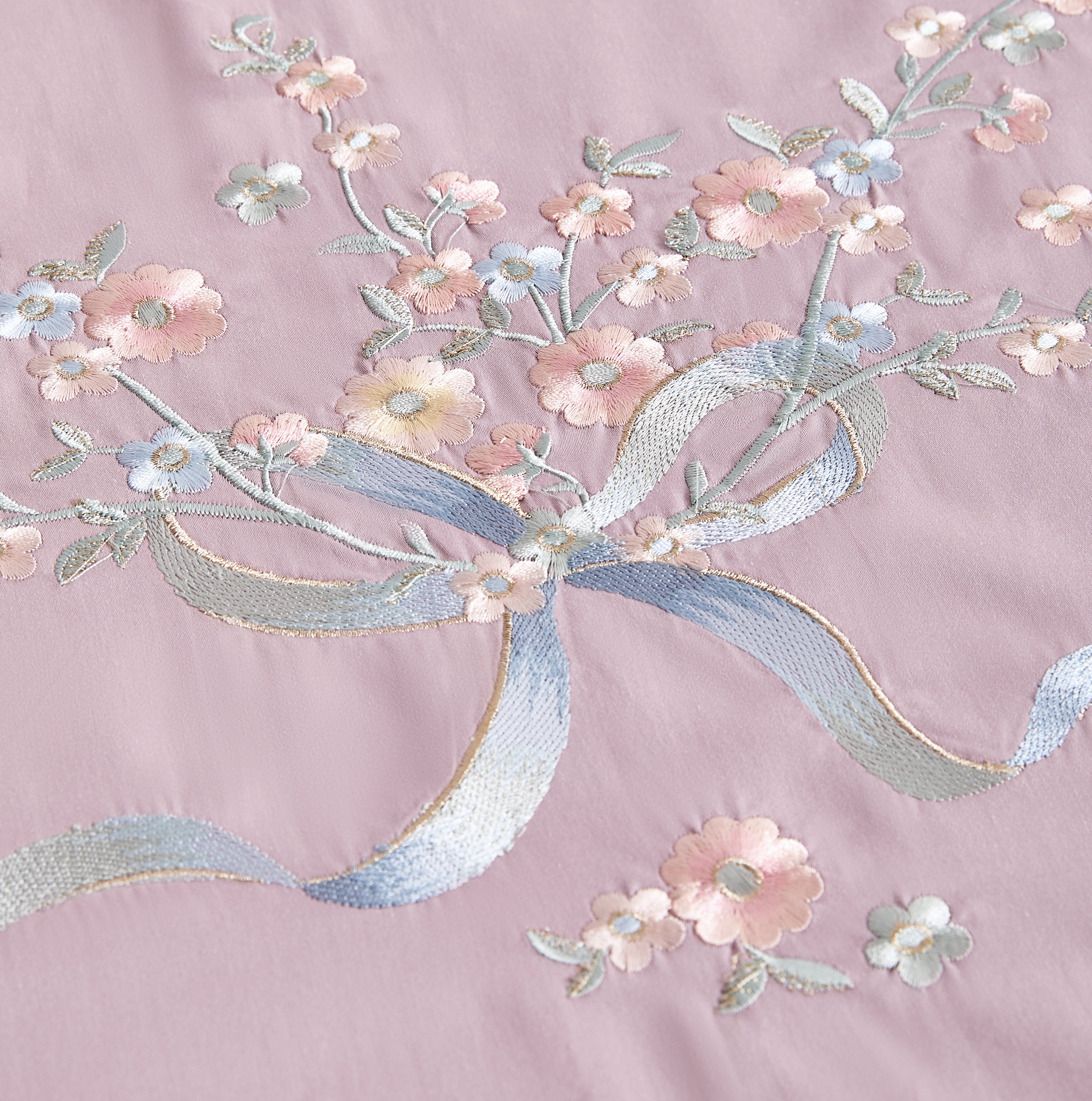 Detailed view of intricate grey and silver floral branch embroidery on white fabric.