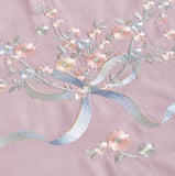 Detailed view of intricate grey and silver floral branch embroidery on white fabric.