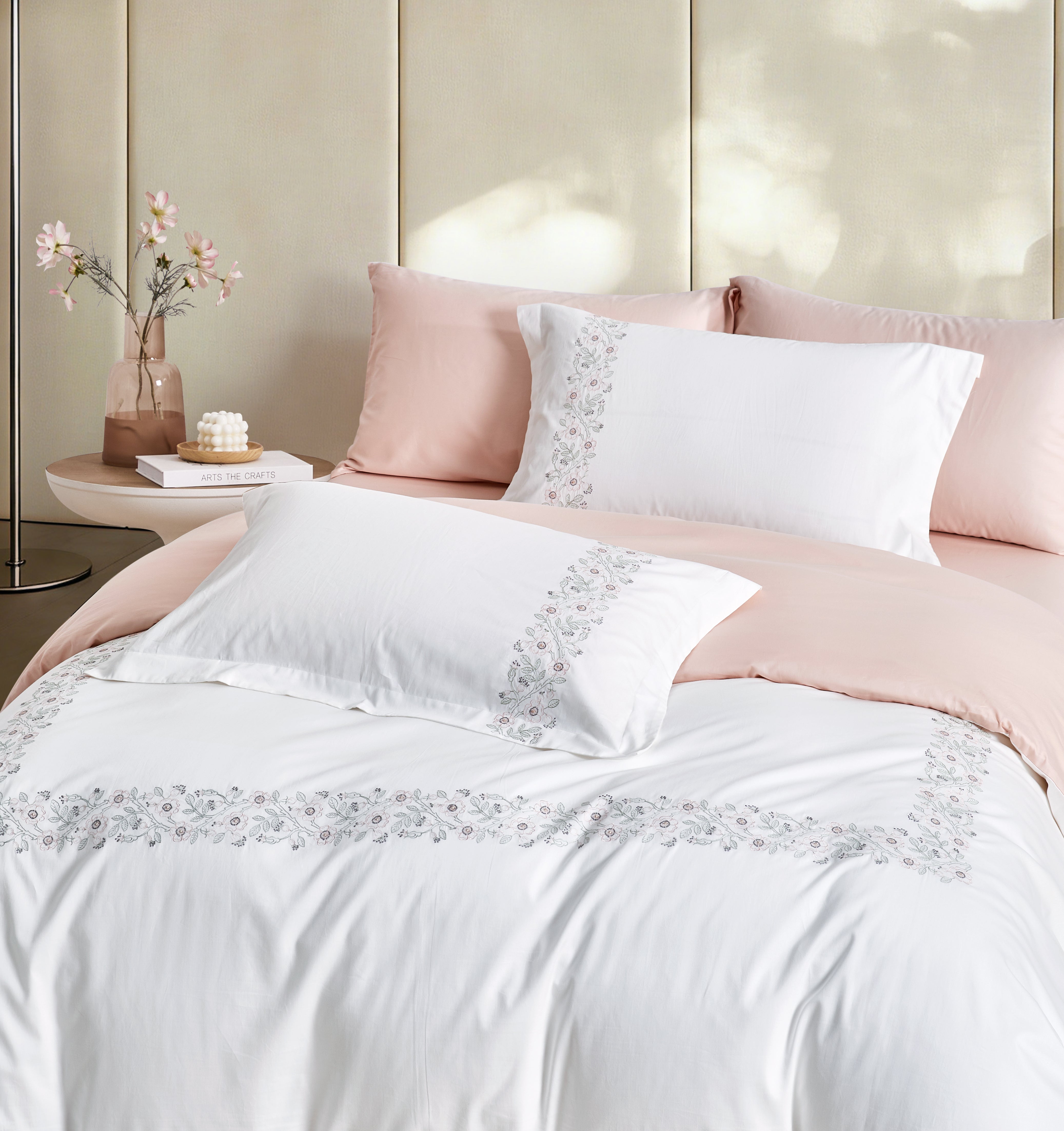 Stacked white pillowcases featuring elegant vertical blue and gold floral embroidery.