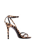 Inner side view of a leopard print strappy heel against a neutral background, highlighting the height of the stiletto and the buckle closure.
