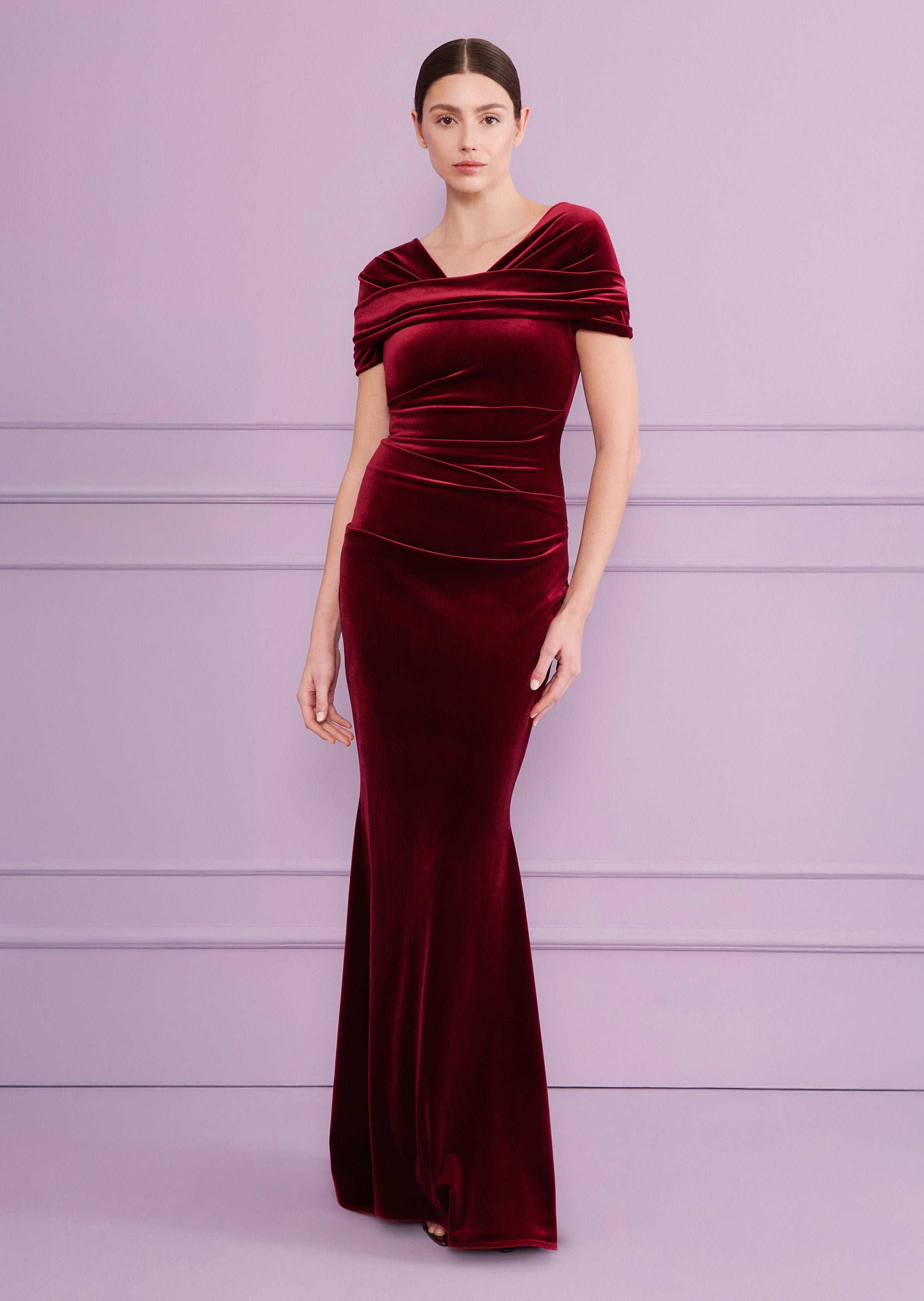 Burgundy velvet long dress with a draped off-the-shoulder neckline, ruched bodice, and a fitted silhouette that flares at the