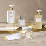 White hand cream tube with a gold-toned square cap featuring an embossed X, and a white label with black text.