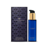 Deep blue rectangular body lotion bottle with gold-toned pump and black dispenser, next to its dark blue box with intricate p