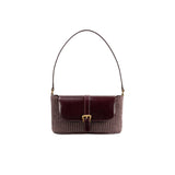 Front view of the BY FAR Miranda baguette bag featuring a purple grape-colored woven raffia body, a smooth dark leather front flap, and a gold buckle against a grey background.