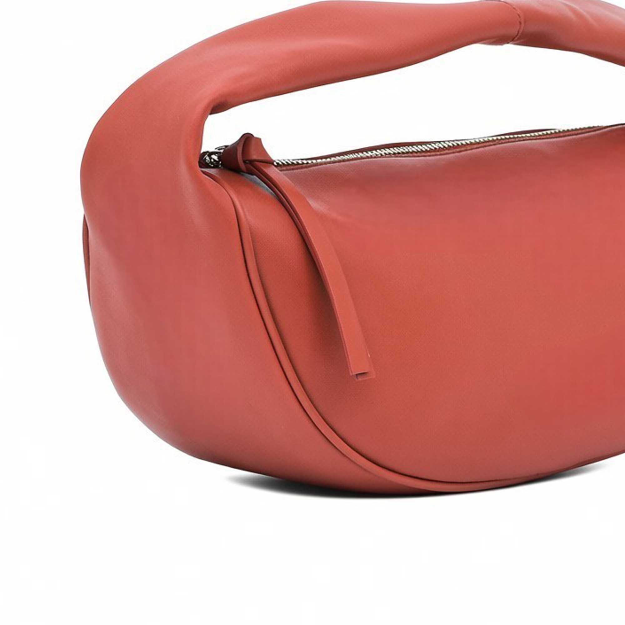 Close-up detail shot of the smooth burnt orange leather, zipper pull, and padded handle attachment of the By Far bag at BLUE SALON.