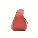 Side profile view of the burnt orange By Far leather handbag, highlighting its triangular base and smooth structure at BLUE SALON.