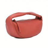 Three-quarter front view of the curved burnt orange leather shoulder bag by By Far, showing the zipper detail, available at BLUE SALON.