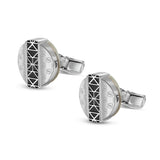 Pair of silver-toned cufflinks. Each round face features a black geometric pattern, 'S' monograms, and a creamy mother-of-pea