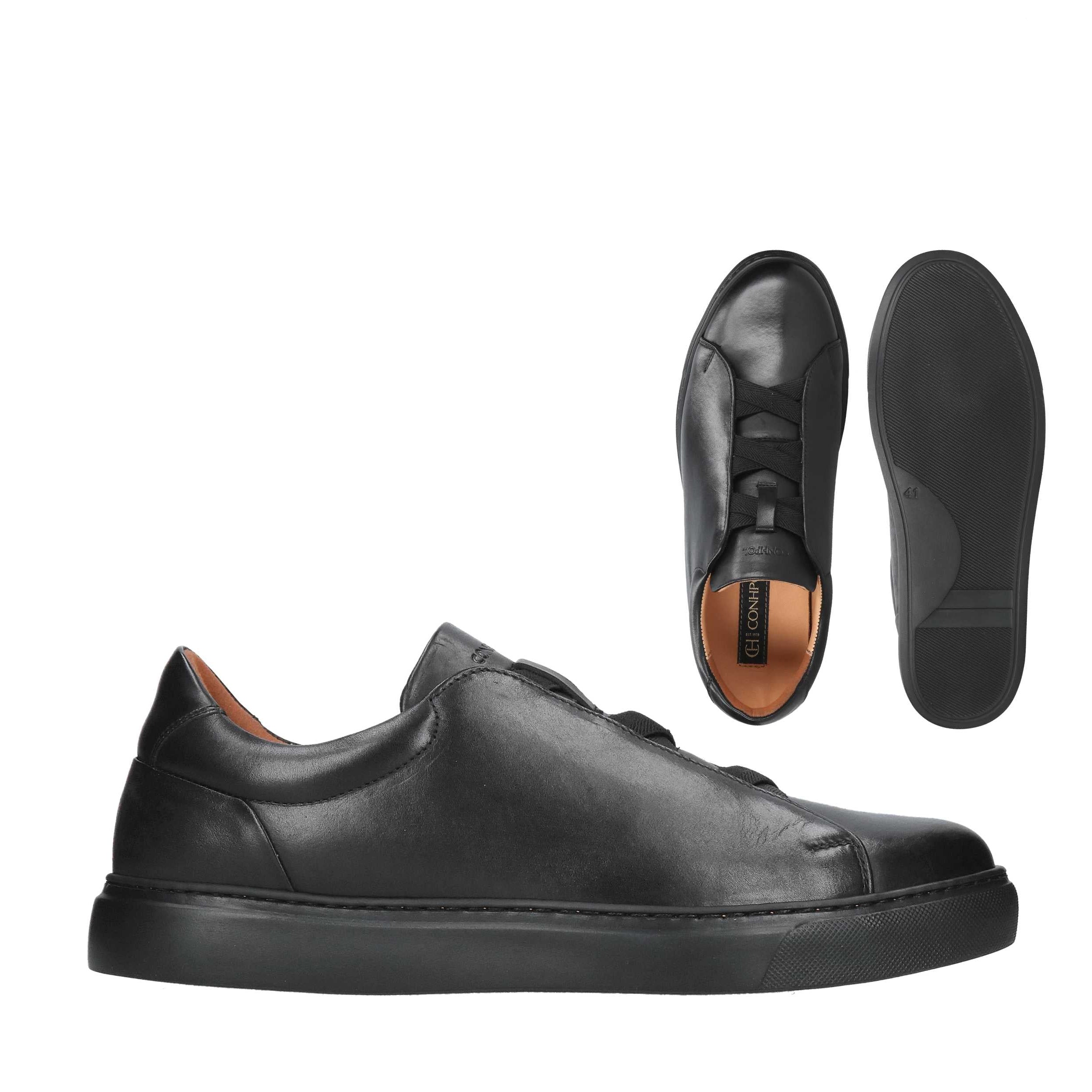 Black leather low-top sneakers with black laces and flat black rubber soles. One shoe shows a brown-tan insole.