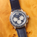 Silver-toned watch with a dark blue dial, three white sub-dials, and a date window. Features a dark blue crocodile-embossed l