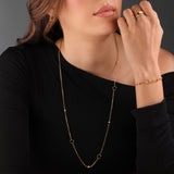 Long gold-toned chain necklace with small clear crystals and dark-colored open C-logo charms spaced along its length.