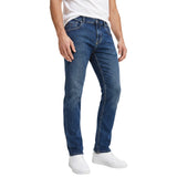 Three-quarter studio shot of a male model from the waist down wearing the Eden Park slim-fit dark indigo jeans, styled casually with a white t-shirt and white leather sneakers.