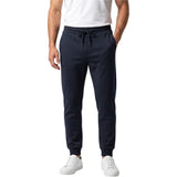 A man wearing navy blue jogger sweatpants with a drawstring waist, paired with a white t-shirt and white sneakers, shown from the waist down on a white background.