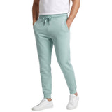 A person wearing mint green jogger sweatpants with a drawstring waist, paired with a white t-shirt and white sneakers, shown from the waist down on a white background.