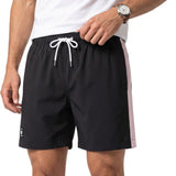 Close-up mid-section studio shot of a male model wearing the black and pink Eden Park swim shorts, paired with a white t-shirt and a leather-strap watch.