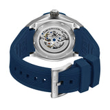 Silver-toned stainless steel watch with a blue ribbed silicone strap. Case back reveals mechanical movement. Silver-toned buc
